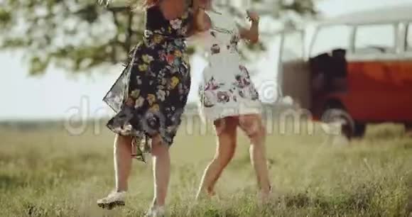 两个年轻的女性穿着复古的裙子在大自然中跳舞背景是一辆漂亮的复古巴士视频的预览图