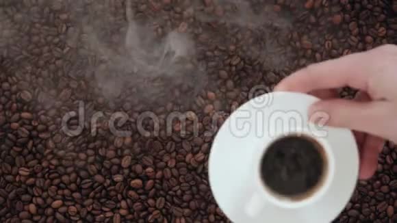 一束咖啡豆小心翼翼地用手端上一杯芳香的咖啡加上奶油和烟熏味视频的预览图