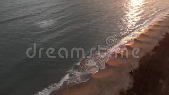 空中俯瞰金色的日落海浪拍打着海岸水面上有美丽的倒影远处有一个视频的预览图