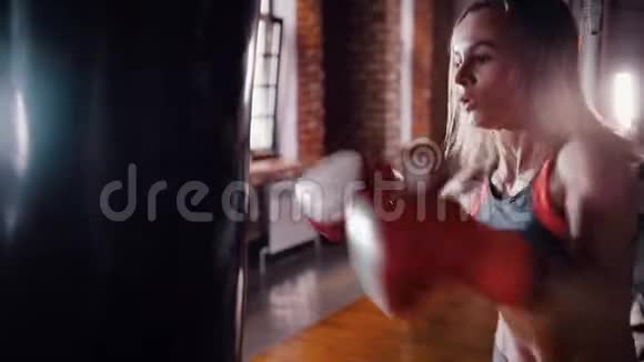 一个好斗的女拳击手在健身房打拳击袋视频的预览图