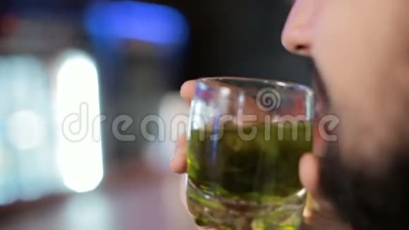 布鲁内特先生坐在酒吧喝一杯加冰和威士忌的绿色苹果酒精饮料视频的预览图