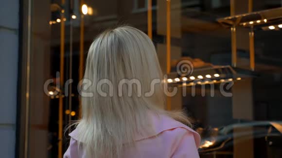 年轻漂亮的金发女郎看着精品橱窗视频的预览图