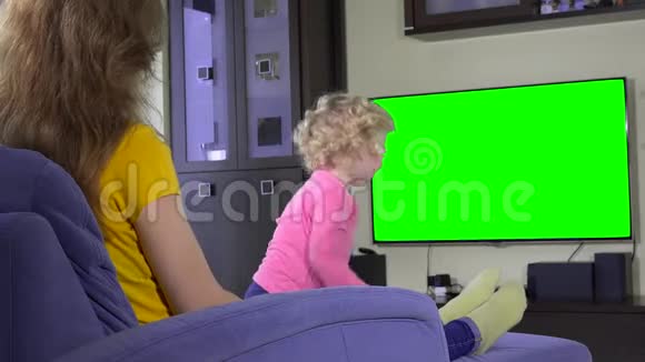 妈妈和她淘气的女儿在看电视绿色彩色键屏视频的预览图