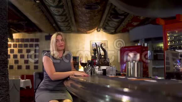 优雅寂寞的女人在酒吧柜台旁喝酒视频的预览图