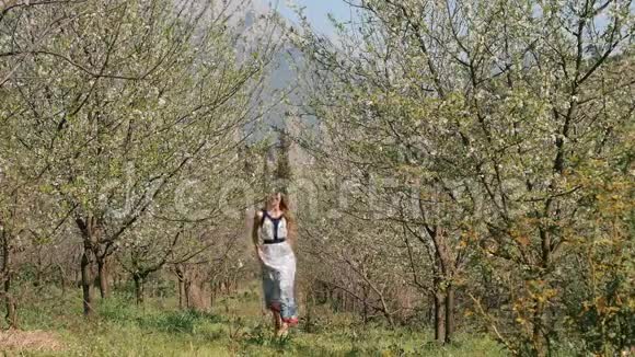 春暖花开的花园里穿着长裙跳跃的年轻美女视频的预览图