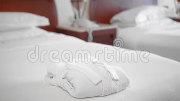 一位未被认出的成年高级妇女把一条完美的白色毛巾放在床上的一件白色浴袍旁边视频的预览图
