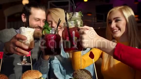 四个快乐的朋友在咖啡馆里喝着爽朗的鸡尾酒和柠檬水视频的预览图