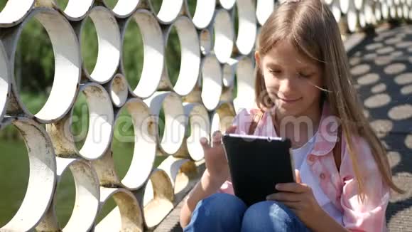 在公园玩平板电脑小女孩在大自然中使用户外智能手机视频的预览图