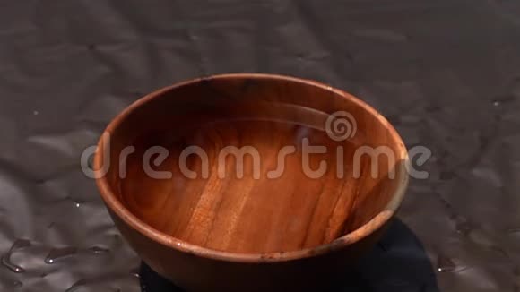 黑暗背景下的木碗里掉进水里的橘子视频的预览图