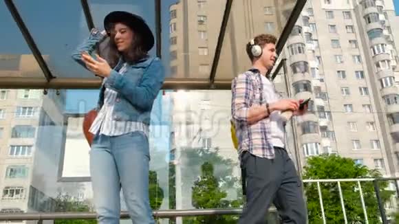 人们站在公共汽车站带着手机在等城市巴士视频的预览图