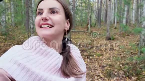 一个年轻的女人在春天的森林里愉快地在电话里自拍微笑着慢点关门视频的预览图