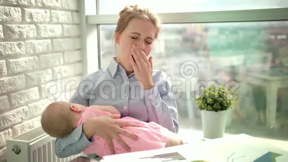 疲惫的女人和熟睡的孩子打哈欠工作场所有孩子的睡眠妈妈视频的预览图