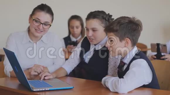 老师帮助学生在笔记本电脑上完成任务计算机课上的课视频的预览图