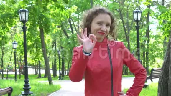 穿着红色皮夹克的年轻女子挥手示意绿园视频的预览图