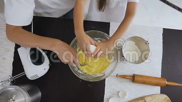 上景小女孩在厨房帮妈妈把鸡蛋打成碗把面团搅拌成饼干家庭视频的预览图