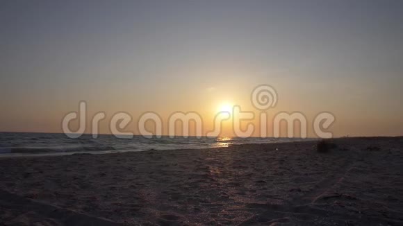 两个年轻的女人正沿着一片荒芜的海滩朝大海上的夕阳跑去视频的预览图