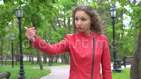 穿红色夹克的年轻女子邀请别人来公园视频的预览图