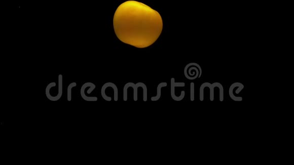 一个黄色的西红柿躺在透明的水中黑色的背景视频的预览图