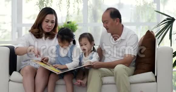 父亲母亲和小女儿在客厅的沙发上读本孩子的书视频的预览图