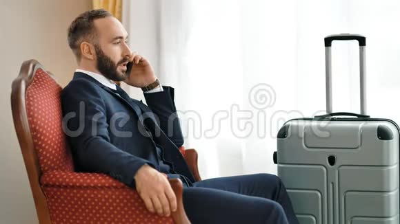 自信时尚的男商人在酒店房间讨论使用智能手机的问题视频的预览图