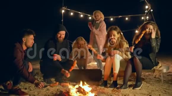 海滩美食年轻人在篝火边做肉制品边跳舞边享受露天度假视频的预览图