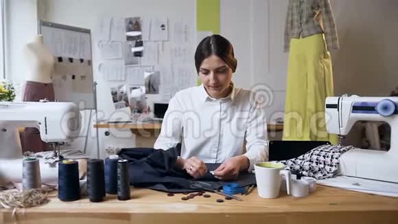 年轻的女裁缝在缝纫工作室缝一块布视频的预览图