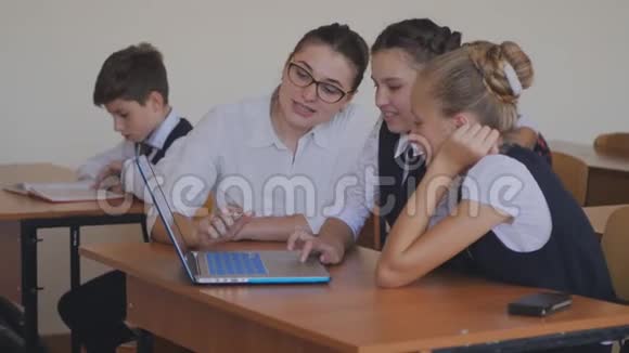 老师帮助学生在笔记本电脑上完成任务计算机课上的课视频的预览图
