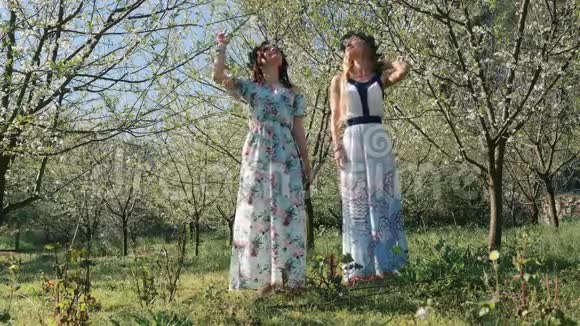 年轻漂亮的女人穿着长裙在春天的树间开花视频的预览图