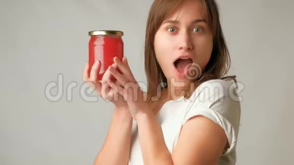 年轻貌美的女人在镜头前兴奋地拿出一罐令人惊讶的红色鱼子酱视频的预览图