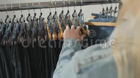 各种各样的女人牛仔裤挂在衣架上女人在商店里挑选衣服双手合拢视频的预览图
