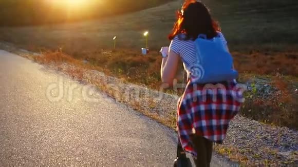 女孩骑着电动滑板车在日落的路上慢的莫后景视频的预览图