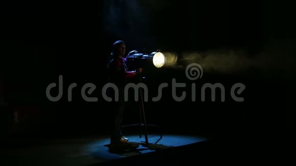 一位年轻的女性照明者从聚光灯中描绘出一束光并引导一束光视频的预览图