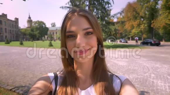 漂亮的年轻女子白天在公园的视频室里聊天手里拿着相机交流理念视频的预览图