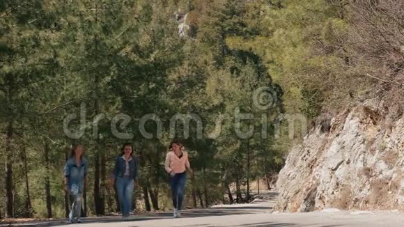 穿牛仔裤的年轻女人在森林路上玩得开心视频的预览图