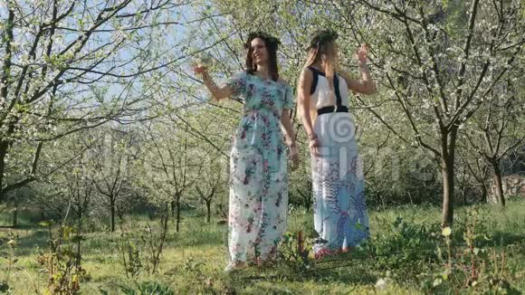 年轻漂亮的女人穿着长裙在春天的树间开花视频的预览图