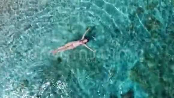 漂浮在清澈海面上的女人的空中景色视频的预览图