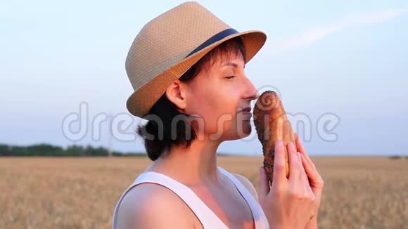 女孩吸入新鲜面包的香气日落时站在麦田里的年轻女子粮食作物农业视频的预览图