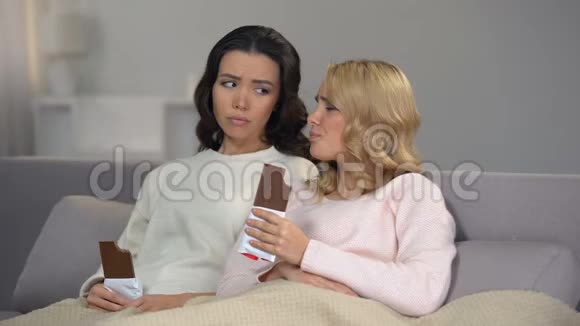 两个沮丧的心碎的女人吃巧克力支撑后刹车视频的预览图