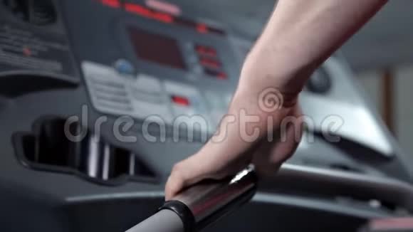 一名男子在健身房的跑步机上慢走检查显示控制台视频的预览图