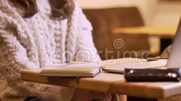 女商人在写笔记本的过程中拍摄的特写镜头在舒适的咖啡里把咖啡带到室内视频的预览图