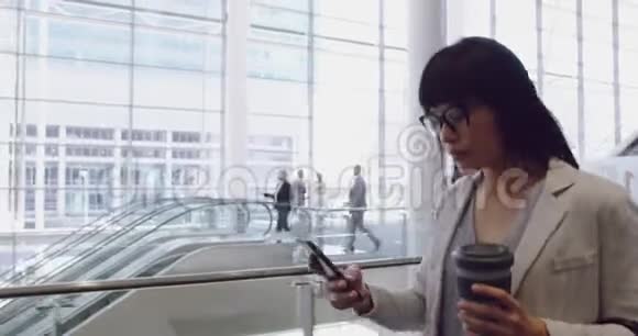 女商人用手机在4k办公室大厅里散步视频的预览图