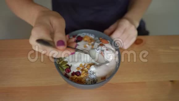 一个年轻女子吃着美味健康的冰沙碗的特写镜头视频的预览图