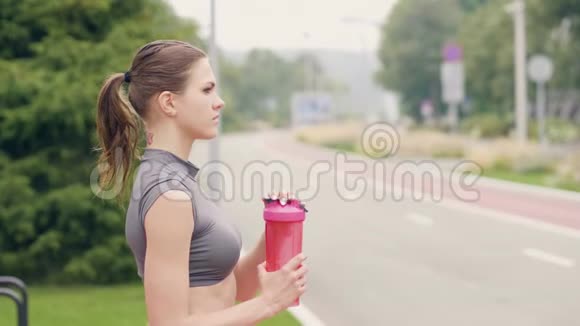 健身妇女在户外运动训练时饮用瓶装水视频的预览图