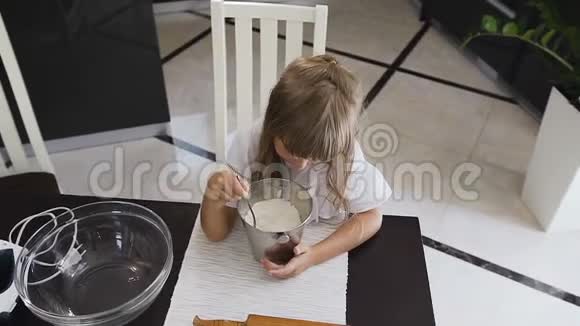 上图是一个小孩在做面团时用勺子搅拌面粉妈妈助手美丽的女孩混在一起视频的预览图