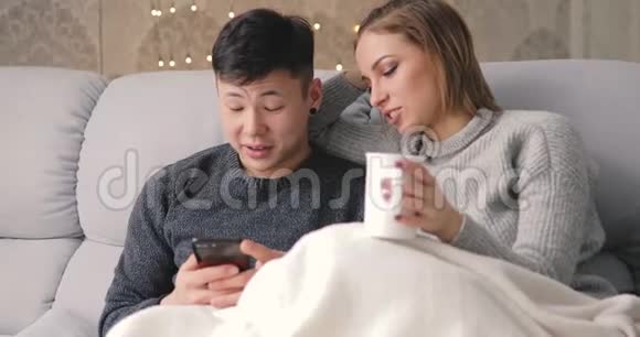 年轻夫妇坐在沙发上用智能手机视频的预览图