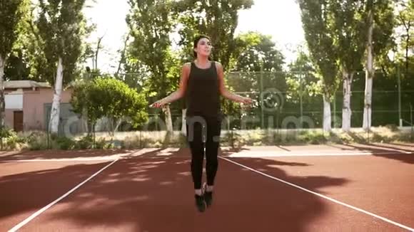 运动的小女孩用跳绳运动跳得很高滚动绳子几次户外体育场视频的预览图