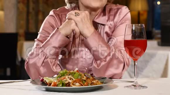 一位面目全非的退休妇女坐在餐厅里桌上摆着蔬菜沙拉和一杯新鲜水果饮料高级的视频的预览图
