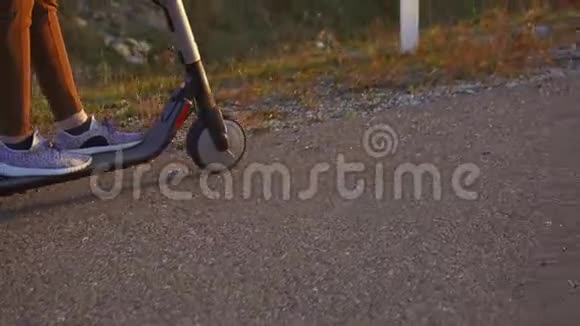 骑着电动滑板车的女孩在路上的沥青上靠近慢的莫视频的预览图