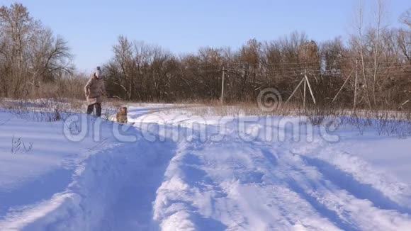 少女在公园的雪路上跑狗冬天女孩和狗玩慢动作视频的预览图