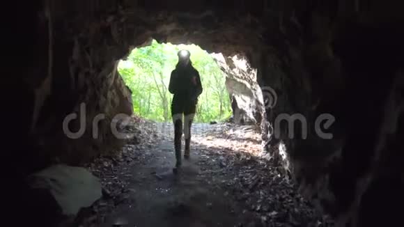 带着手电筒的背包的女旅行者走进了一个黑暗的洞穴视频的预览图
